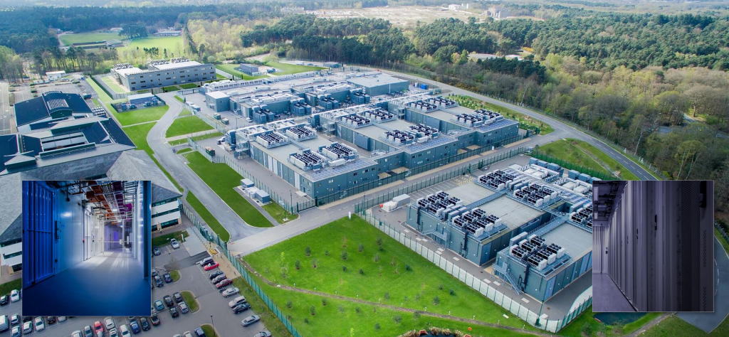 Aerial view of a datacenter campus, featuring expansive buildings equipped with multiple cooling units on the rooftops. Nearby parking areas are filled with cars, and the complex is surrounded by green fields, a pond, and dense forest areas. The facility emphasizes modern infrastructure amidst a natural setting.